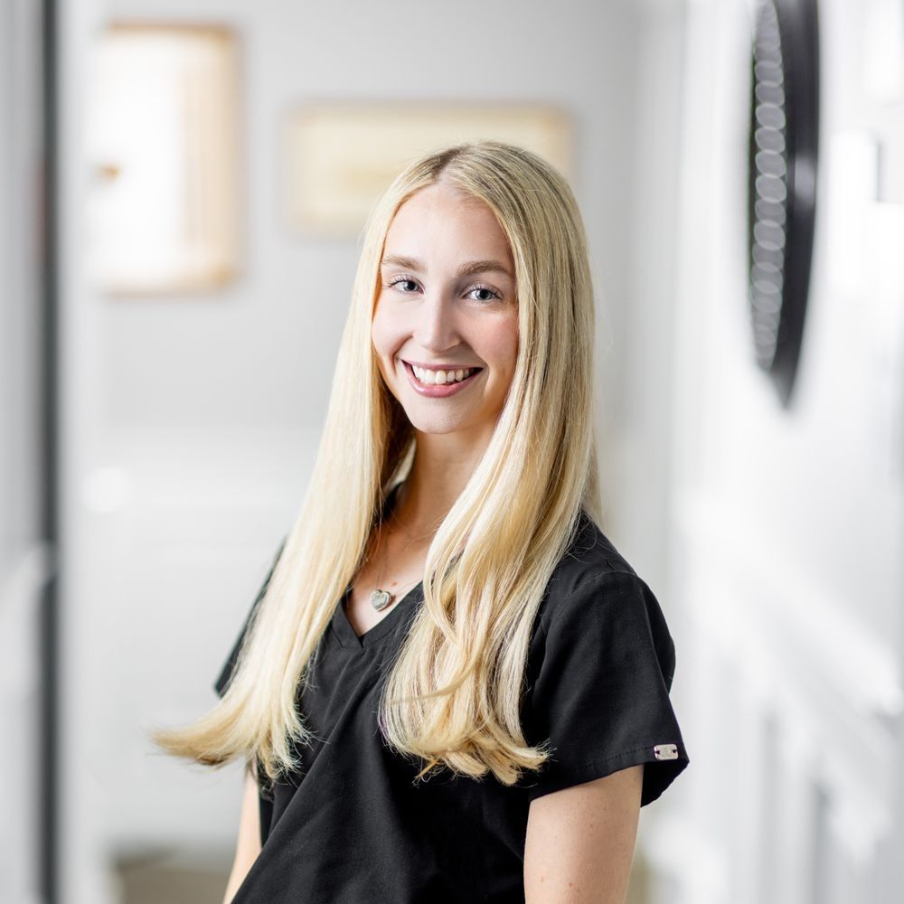 Smiling woman in black scrubs, indoor setting.