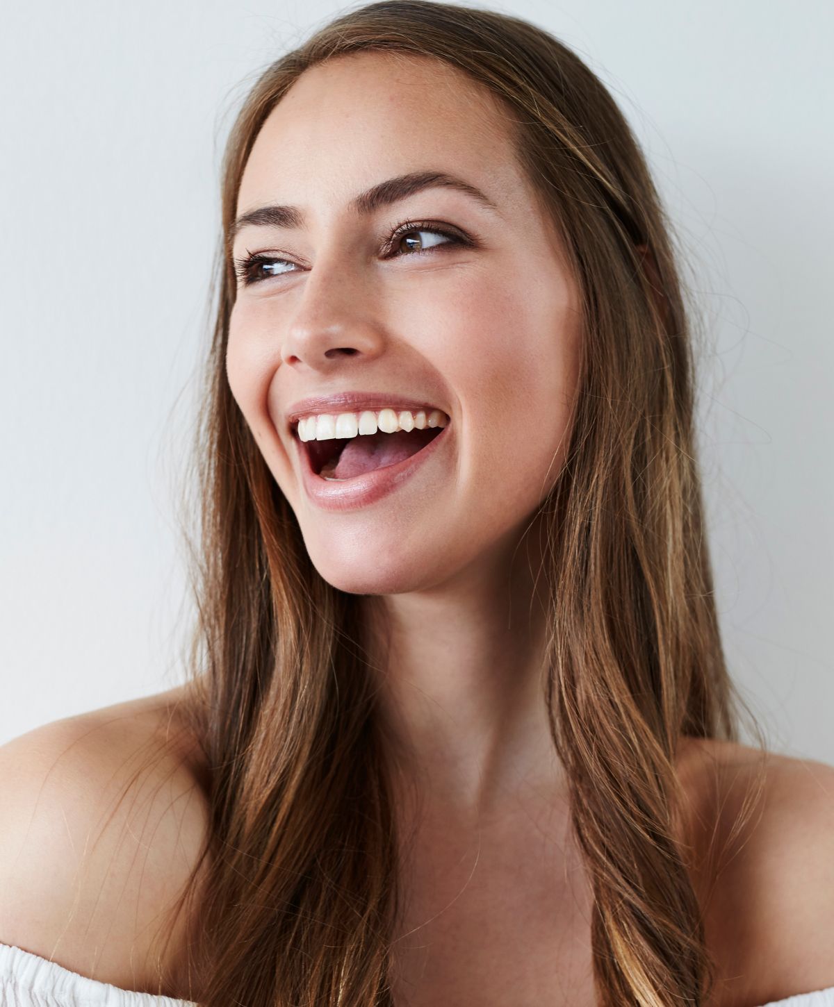 Smiling woman with long hair against white background.