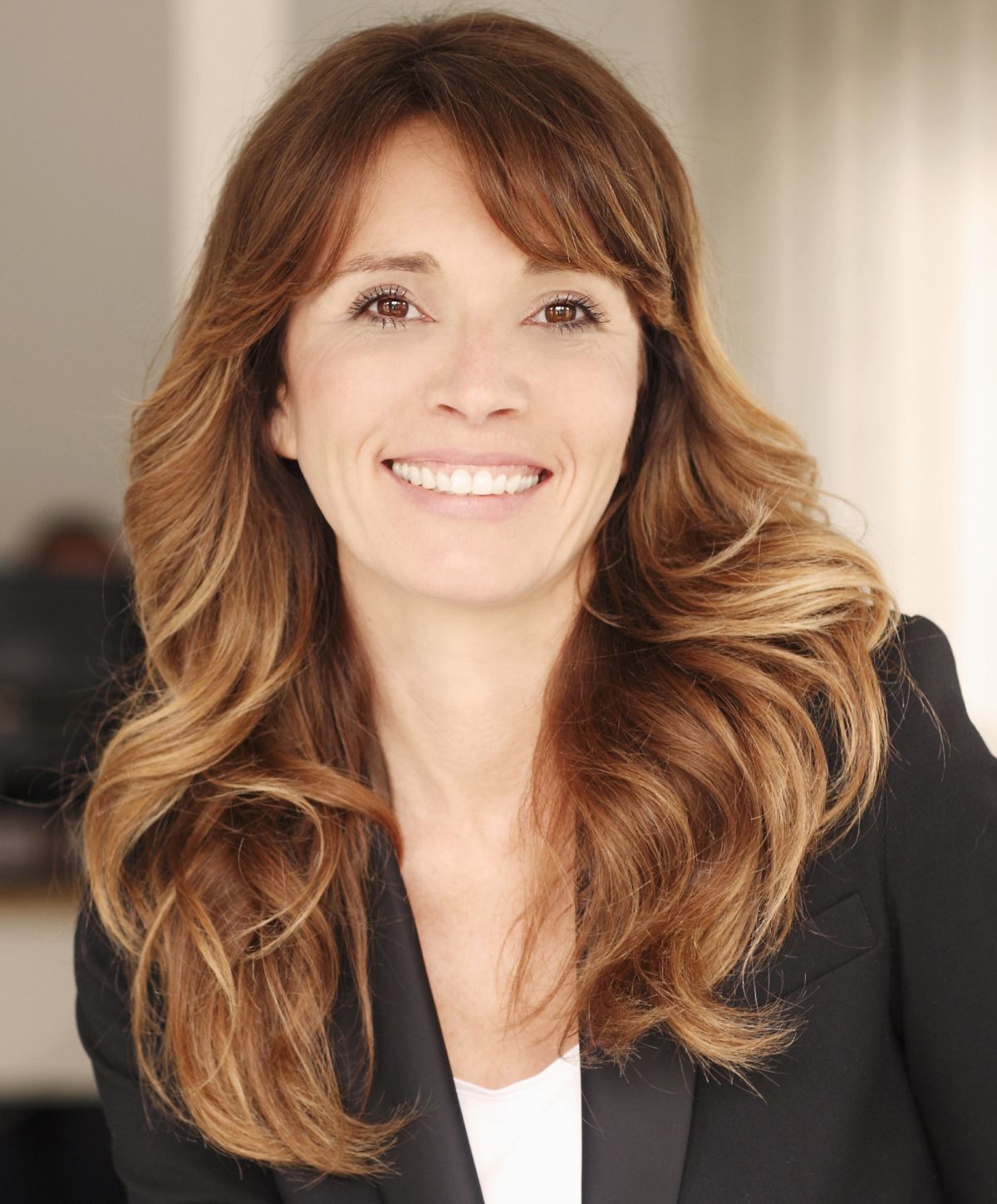 Woman smiling with long, wavy brown hair.
