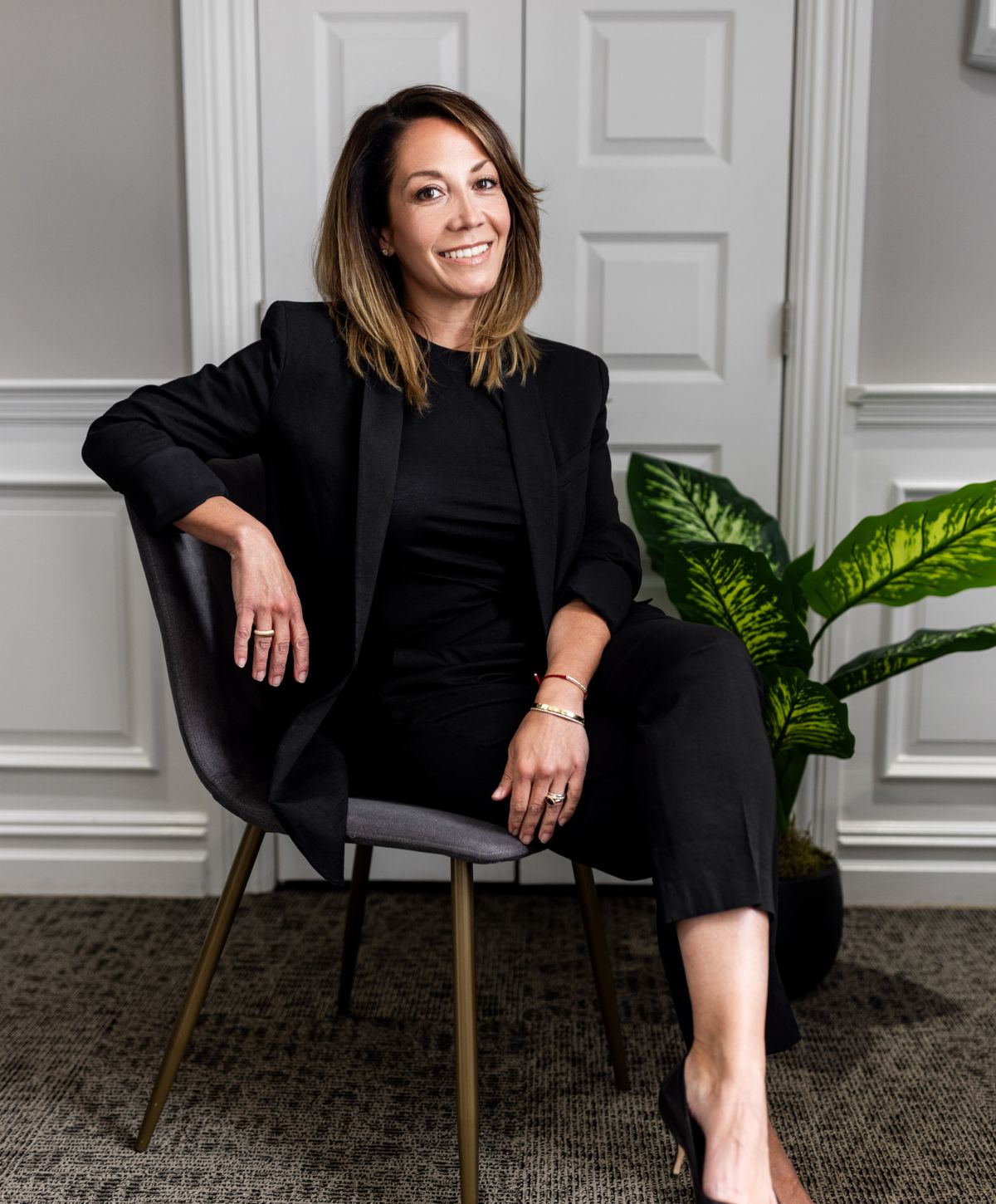 Smiling woman with curly hair in black dress.