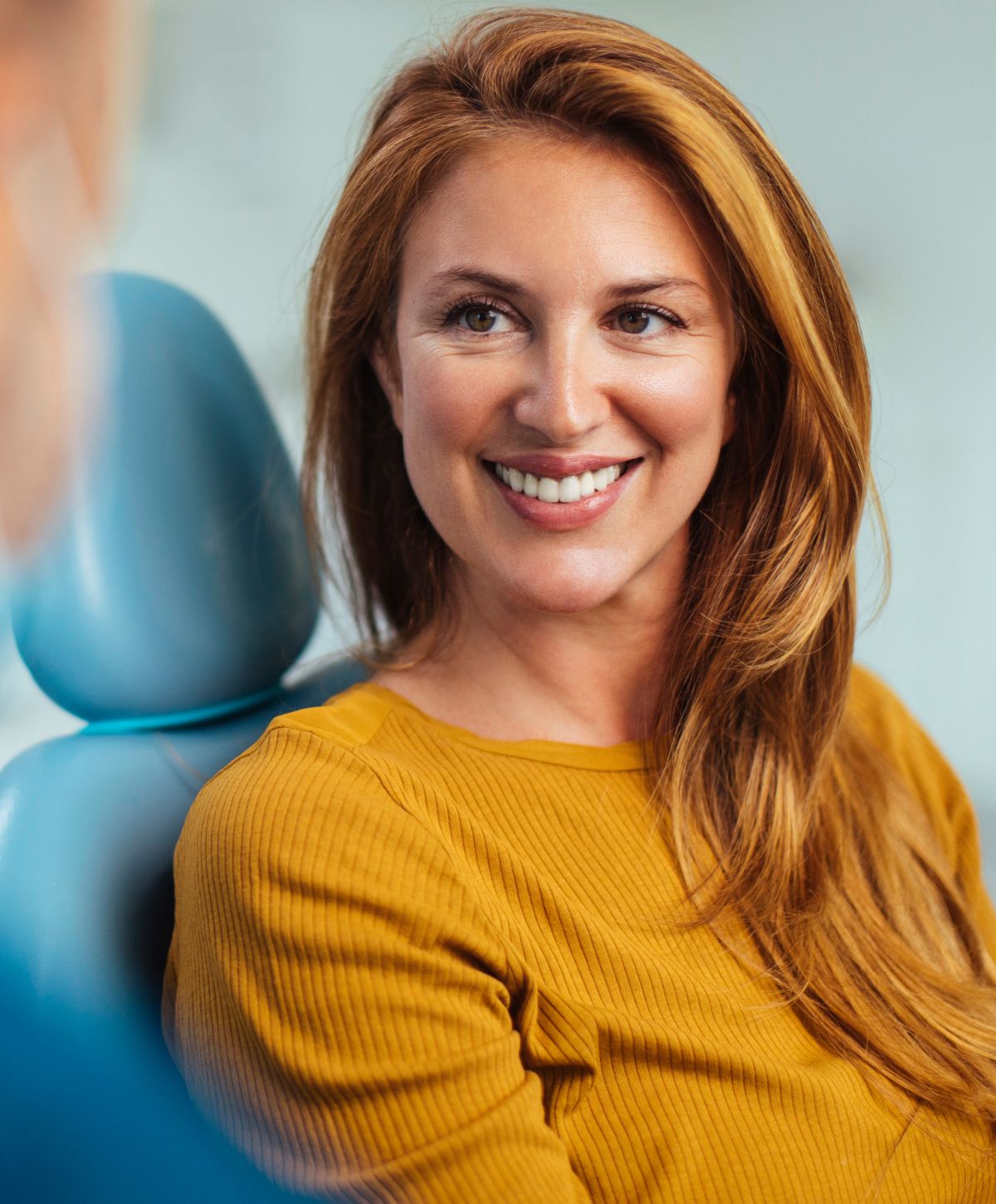 Smiling woman with long hair in yellow shirt