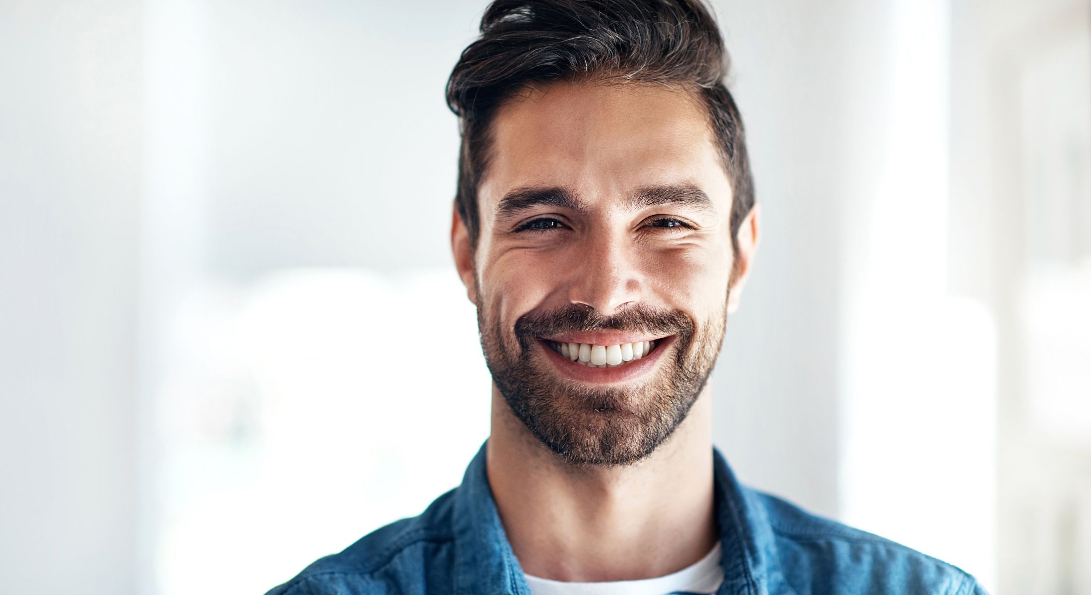 Smiling man with a beard in casual attire.
