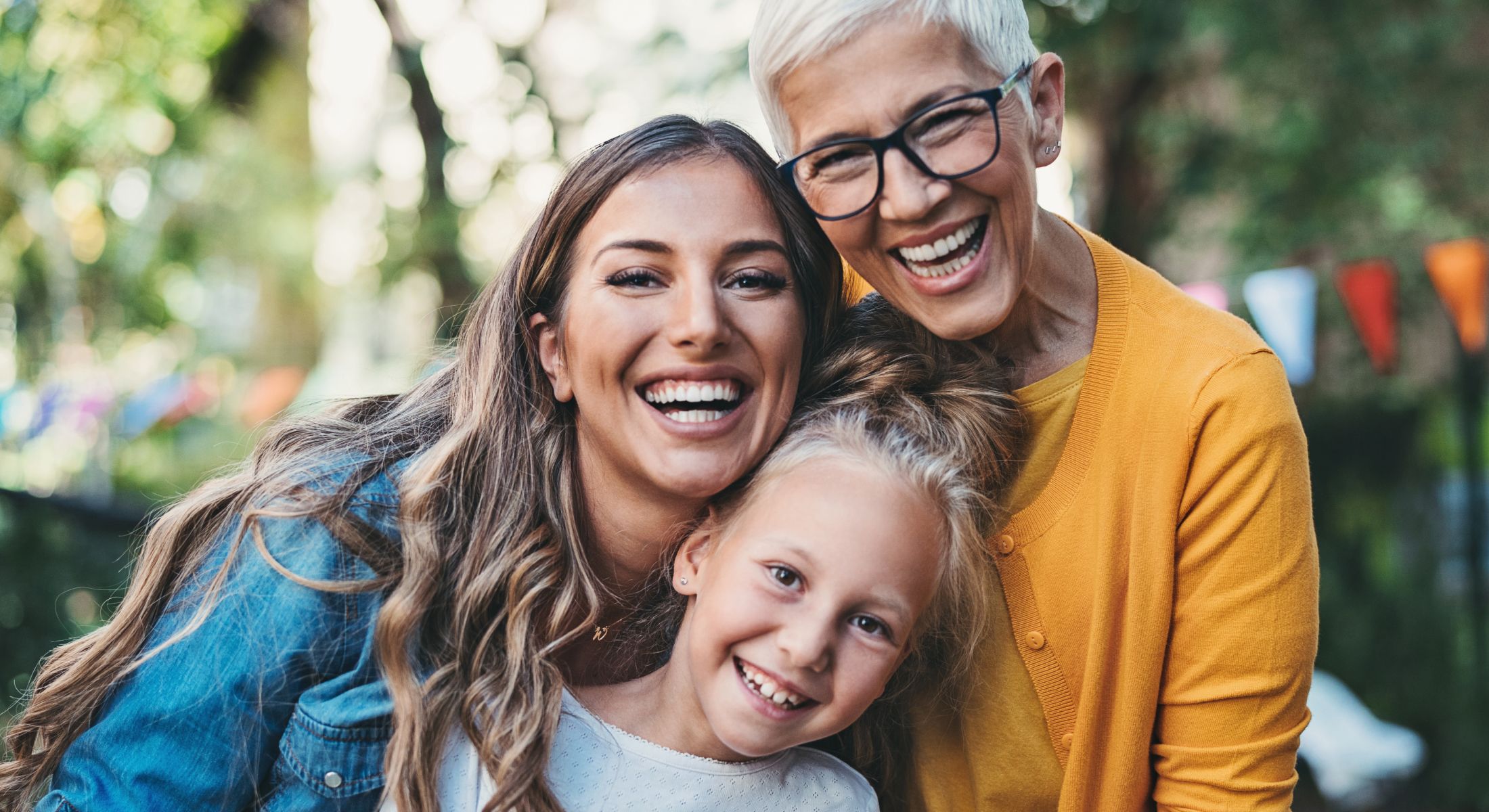 Three generations of women smiling together outdoors