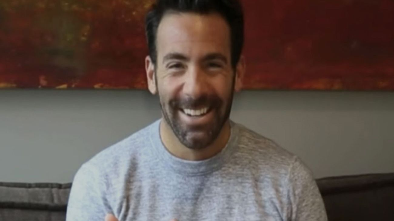 Man smiling casually on a couch.