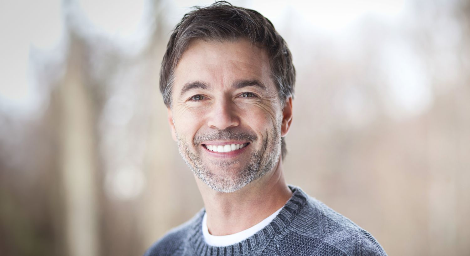 Smiling man in a sweater outdoors.